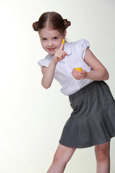 Lovely schoolgirl posing with yellow finger paint — Stock Photo, Image