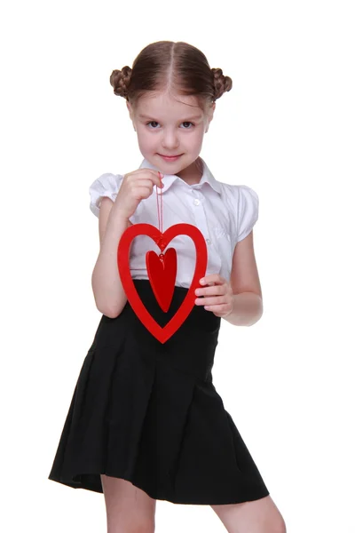 Kavkazská krásná školačka drží symbol červené srdce — Stock fotografie