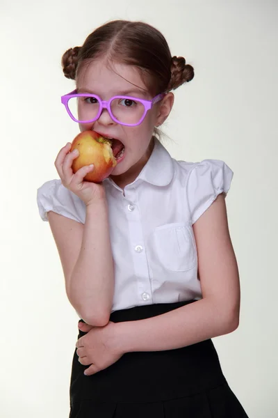 Portret van een schoolmeisje in glazen eten apple — Stockfoto