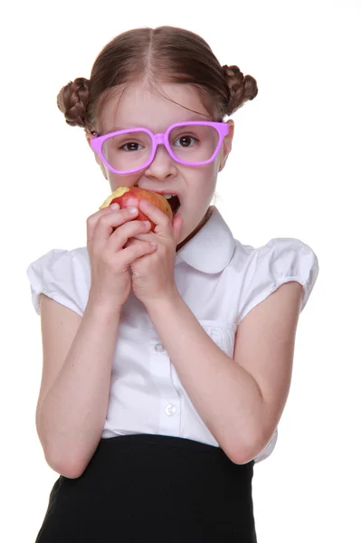 Retrato de una colegiala en gafas comiendo manzana — Foto de Stock