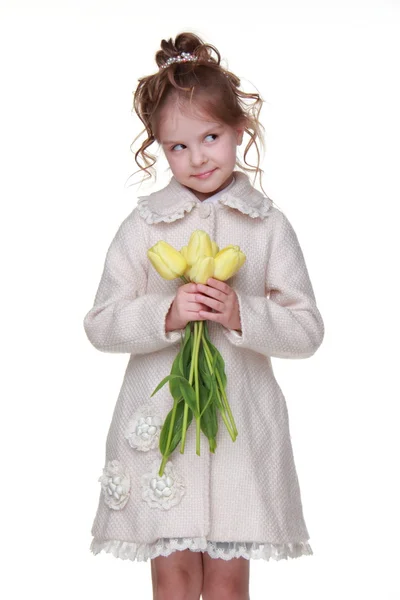 Vacker liten flicka i en kappa håller en bukett tulpaner — Stockfoto
