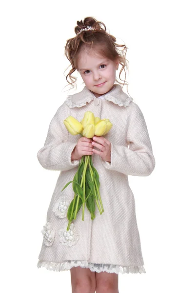 Vacker liten flicka i en kappa håller en bukett tulpaner — Stockfoto