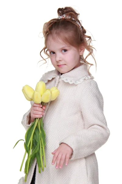 Beautiful little girl in a coat holding a bouquet of tulips — Stock Photo, Image