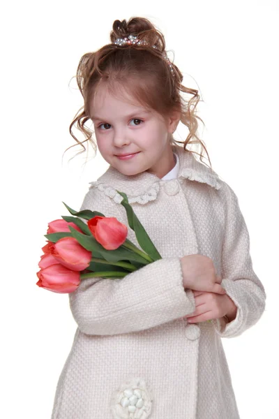 Söt liten flicka i en kappa håller en bukett tulpaner — Stockfoto