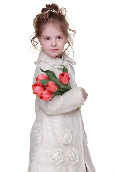 Menina bonito em um casaco segurando um buquê de tulipas — Fotografia de Stock