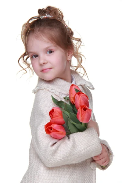 Cute little girl in a coat holding a bouquet of tulips — Stock Photo, Image