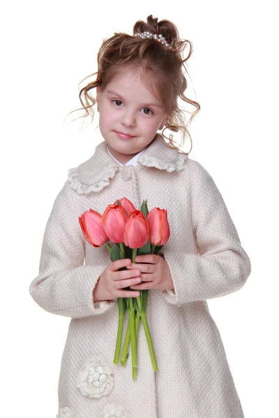 Menina bonito em um casaco segurando um buquê de tulipas — Fotografia de Stock