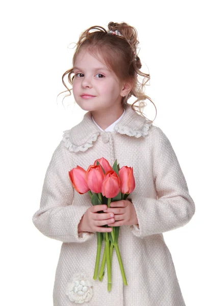 Cute little girl in a coat holding a bouquet of tulips — Stock Photo, Image