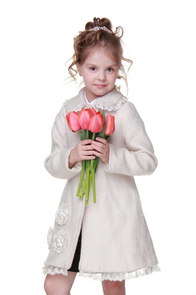 Cute little girl in a coat holding a bouquet of tulips — Stock Photo, Image