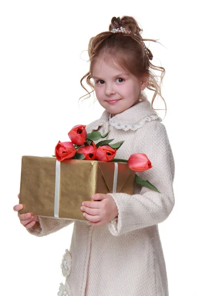 Милая маленькая девочка в пальто с букетом тюльпанов и подарочной коробкой — стоковое фото