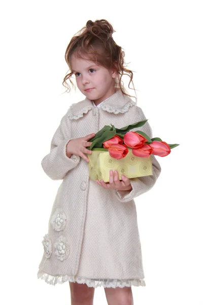 Šťastná holčička v plášti drží kytici tulipánů a dárkový box — Stock fotografie