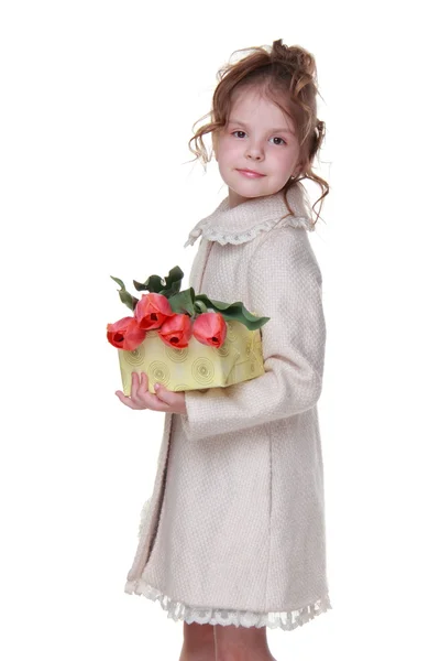 Niña feliz en un abrigo sosteniendo un ramo de tulipanes y una caja de regalo — Foto de Stock