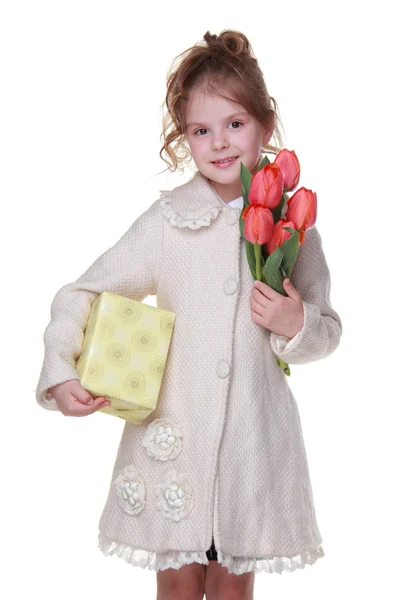 快乐的小女孩，在一件外套，拿一束郁金香和礼品盒 — 图库照片