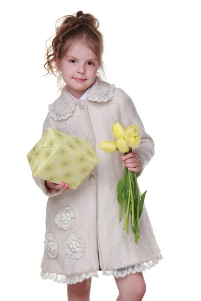 Cute little girl holding a bouquet of tulips and a gift box — Stock Photo, Image