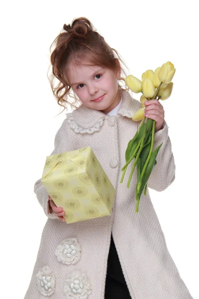 Menina bonito segurando um buquê de tulipas e uma caixa de presente — Fotografia de Stock