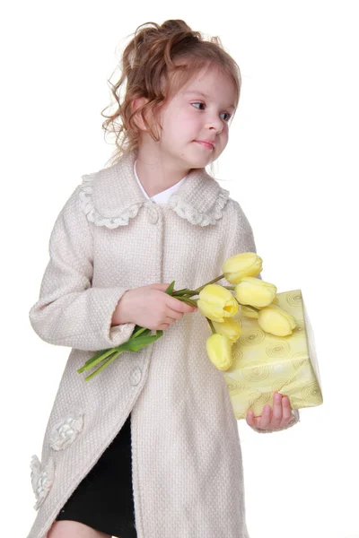 Söt liten flicka som håller en bukett tulpaner och en presentförpackning — Stockfoto