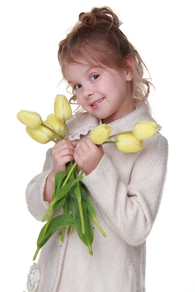 Menina bonito em um casaco segurando um buquê de tulipas — Fotografia de Stock