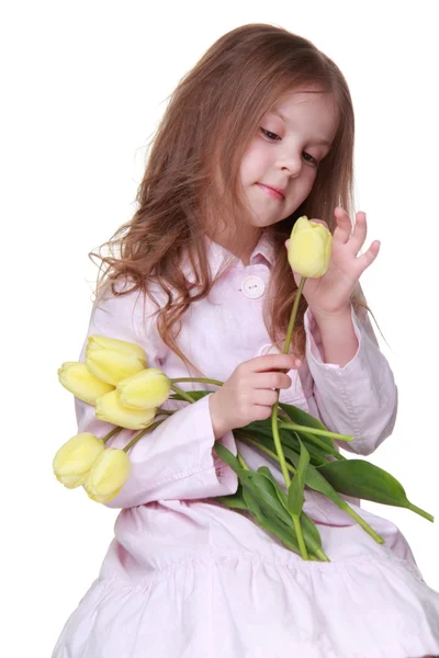 Niedliches kleines Mädchen in einem Kleid mit einem Strauß Tulpen — Stockfoto