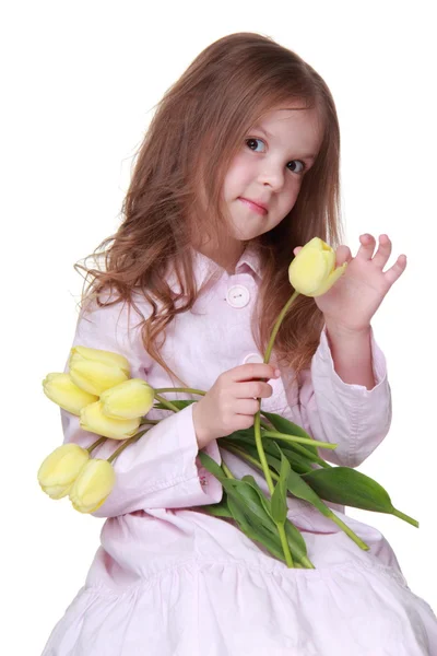 Söt liten flicka i en klänning med en bukett tulpaner — Stockfoto