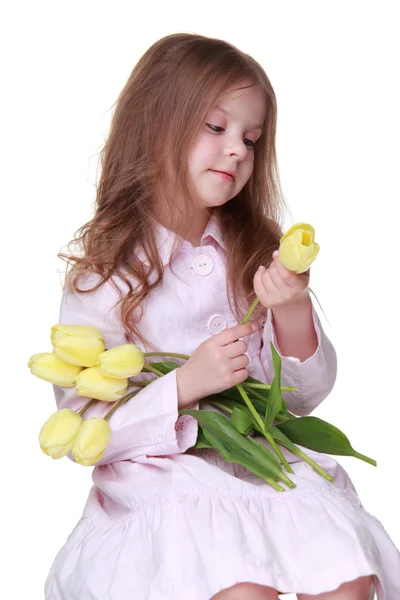 Schattig klein meisje in een jurk met een boeket van tulpen — Stockfoto