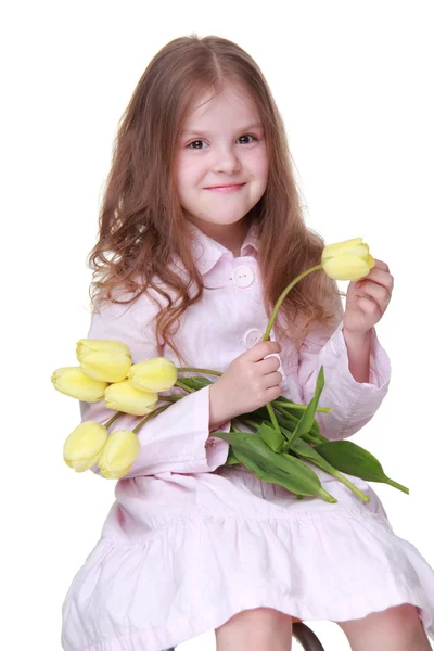 Niedliches kleines Mädchen in einem Kleid mit einem Strauß Tulpen — Stockfoto