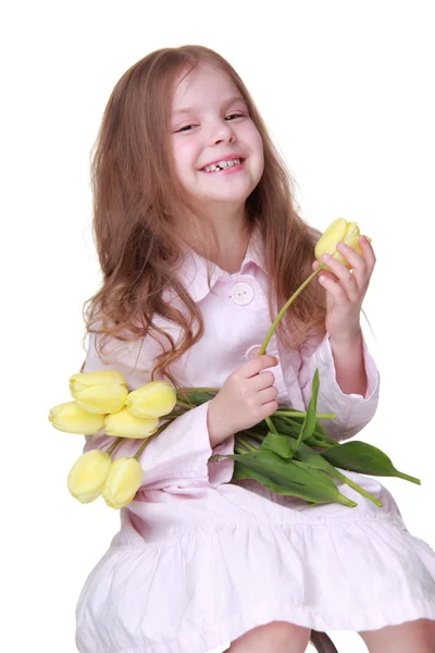 Schattig klein meisje in een jurk met een boeket van tulpen — Stockfoto