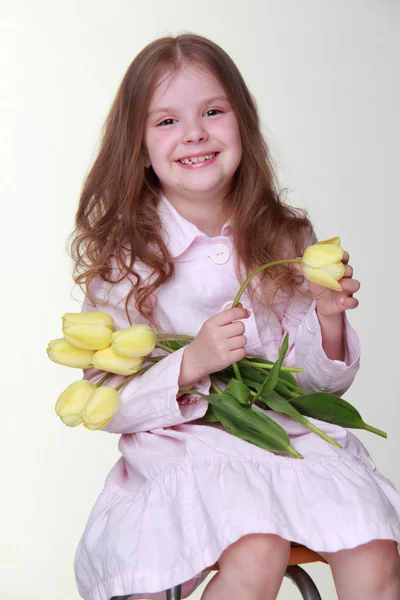 Cute dziewczynka w sukni z bukietem tulipanów — Zdjęcie stockowe