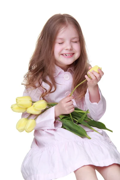 Schattig klein meisje in een jurk met een boeket van tulpen — Stockfoto