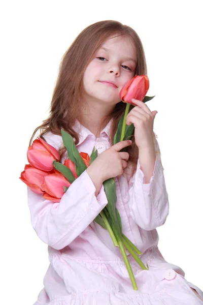 Söt liten flicka i en ljus klänning med en bukett tulpaner — Stockfoto