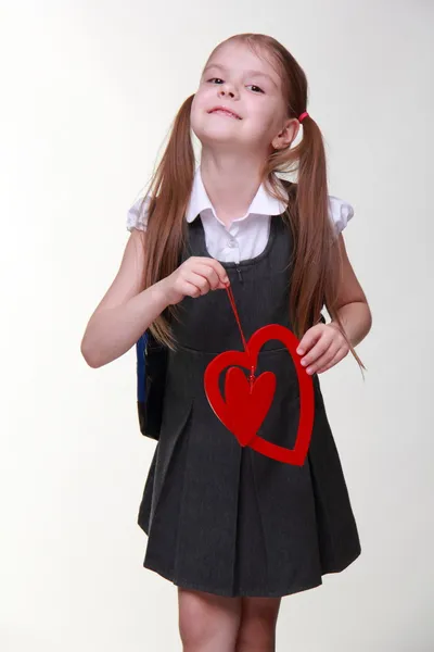 Caucasian lovely schoolgirl holding red heart symbol — Stock Photo, Image