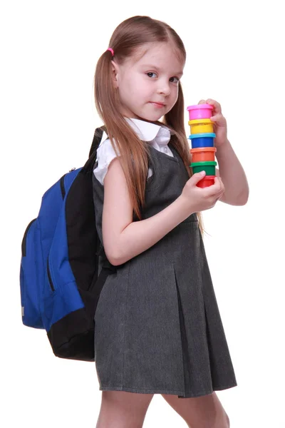 Cute schoolgirl with schoolbag holding paints — Stock Photo, Image
