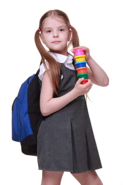 Cute schoolgirl with schoolbag holding paints — Stock Photo, Image