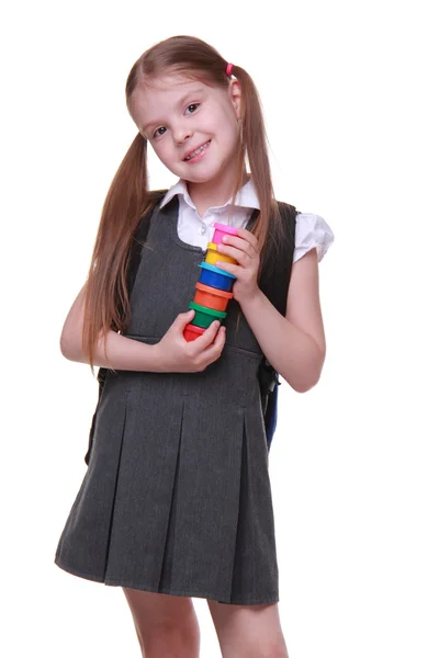 Cute schoolgirl in dress holding paints — Stock Photo, Image