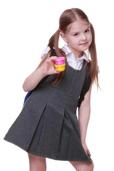 Милая школьница в платье держит краски — стоковое фото