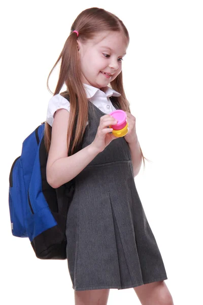 Cute schoolgirl with schoolbag holding paints — Stock Photo, Image