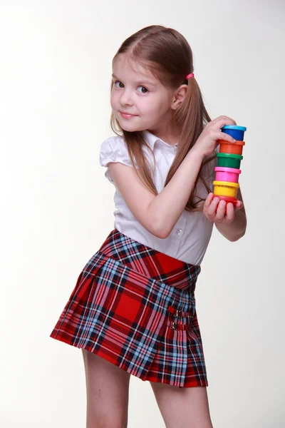 Söt flicka i rutig kjol håller färger — Stockfoto