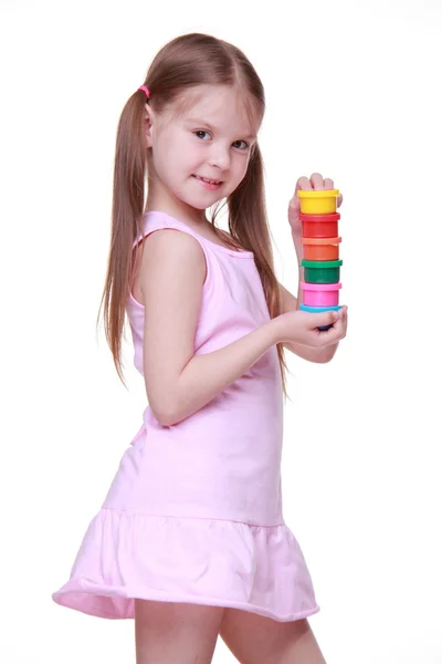 Roztomilá holčička v růžových šatech drží barvy — Stock fotografie