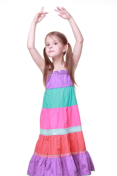 Beautiful little girl in a lovely colorful dress dancing in studio — Stock Photo, Image
