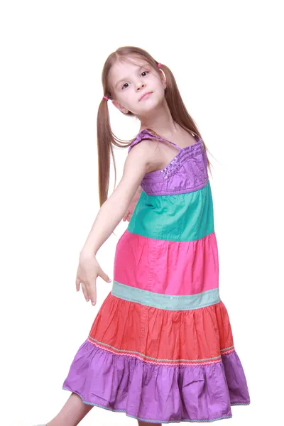 Beautiful little girl in a lovely colorful dress dancing in studio — Stock Photo, Image