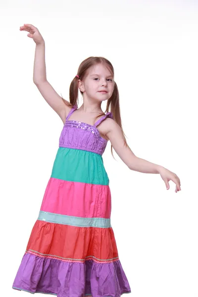 Beautiful little girl in a lovely colorful dress dancing in studio — Stock Photo, Image