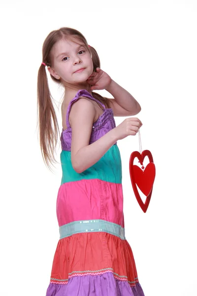 Little girl in a colorful dress posing with heart — Stock Photo, Image