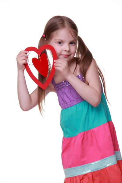 Klein meisje in een kleurrijke jurk poseren met hart — Stockfoto