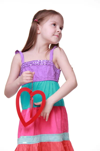 Liten flicka i en färgglad klänning poserar med hjärta — Stockfoto