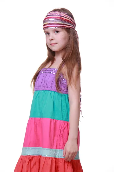 Маленька дівчинка в барвистій сукні позує в студії — стокове фото