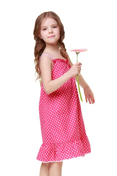 Emocional niña hermosa con una dulce sonrisa en vestido ligero sosteniendo una hermosa flor fresca — Foto de Stock