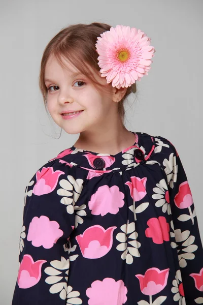 Menina bonita em um vestido brilhante com gerbera fresco em seu cabelo — Fotografia de Stock