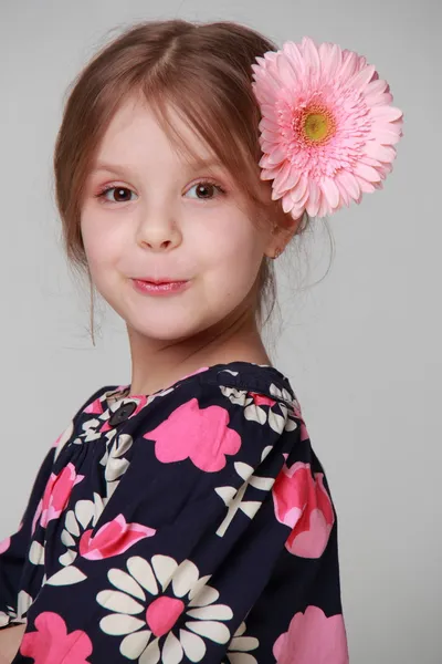 Hermosa niña en un vestido brillante con gerberas frescas en su cabello —  Fotos de Stock