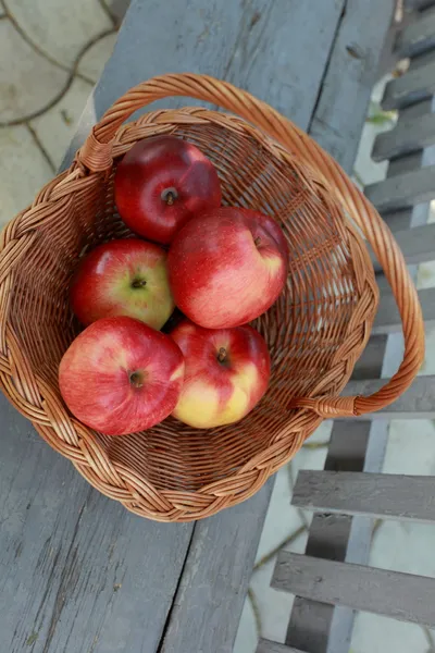 Basket with red apples on a bench,outdoors — Stock Photo, Image