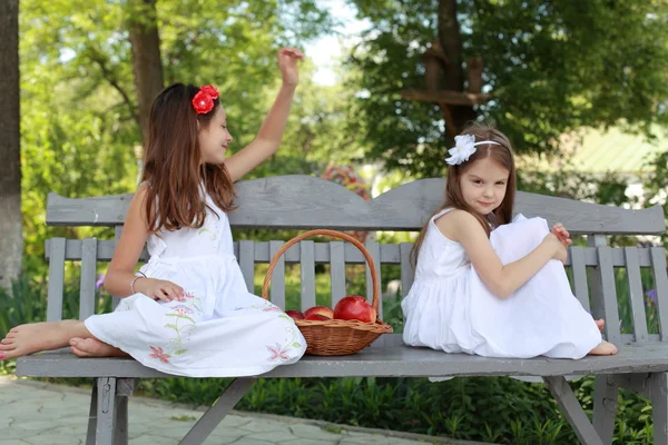 Lovely girls with basket of red apples on a bench — Stok fotoğraf