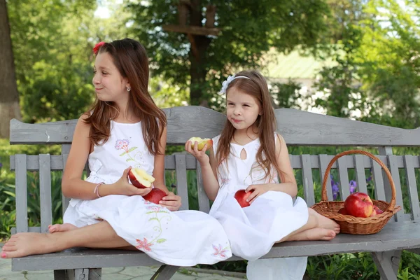 Belle ragazze con cesto di mele rosse su una panchina — Foto Stock